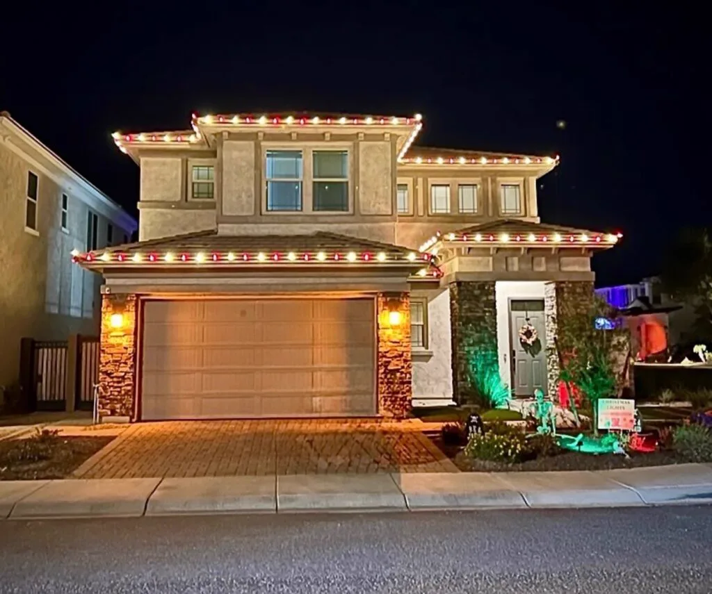 Finished red and white holiday roofline install at night