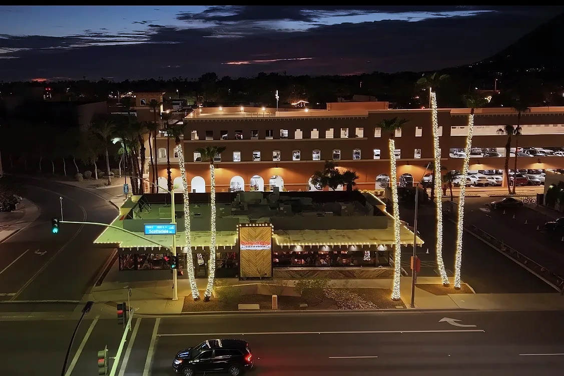 Bourbon & Bones in Scottsdale at night with light-wrapped palm trees and roofline lights
