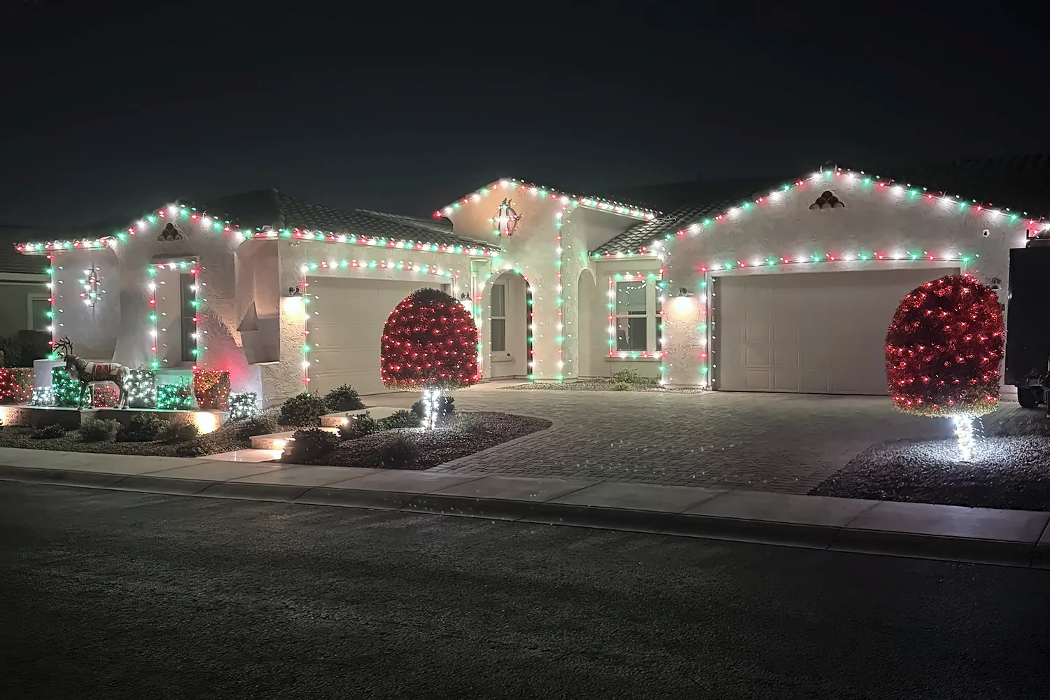 Red, white and green C9 roofline with light-wrapped shrubs