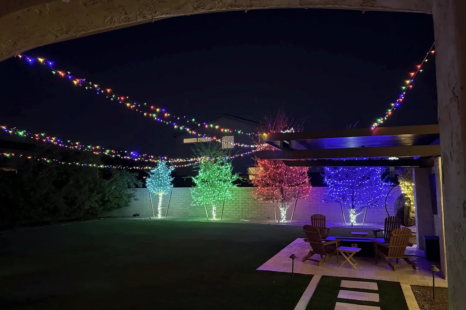 Multicolor string lights and color tree wraps in a backyard