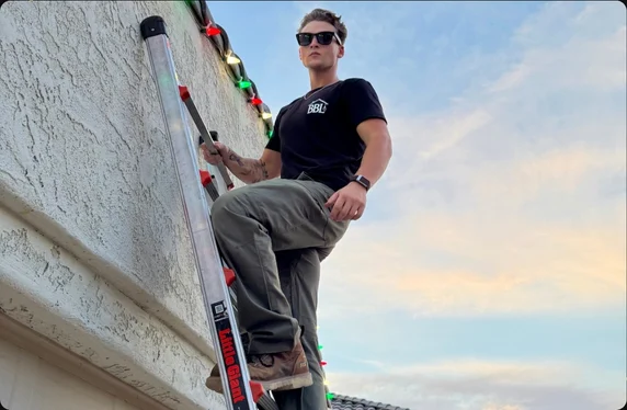 Briggs Brothers Lighting installer on a ladder clipping C9 holiday lights to a Phoenix roofline